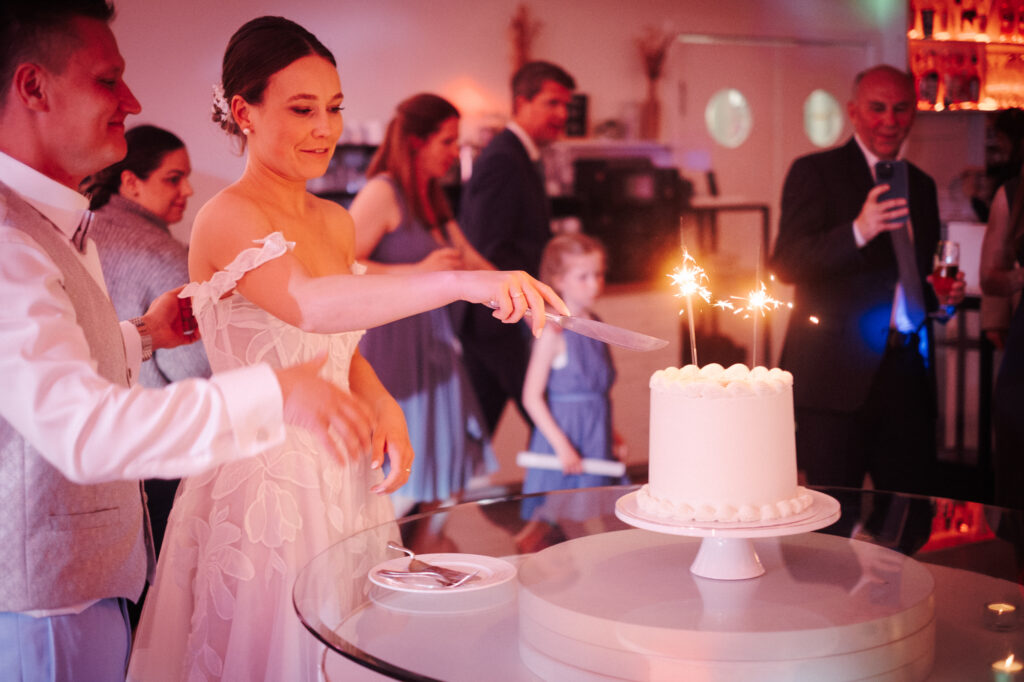 Brautpaar schneidet Hochzeitstorte mit Wunderkerzen an