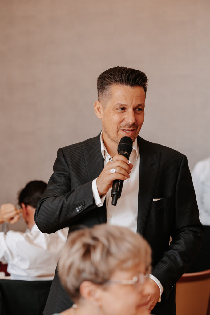 Hochzeitsmoderator Danilo Gobbetto spricht bei einer Hochzeitsfeier ins Mikrofon.